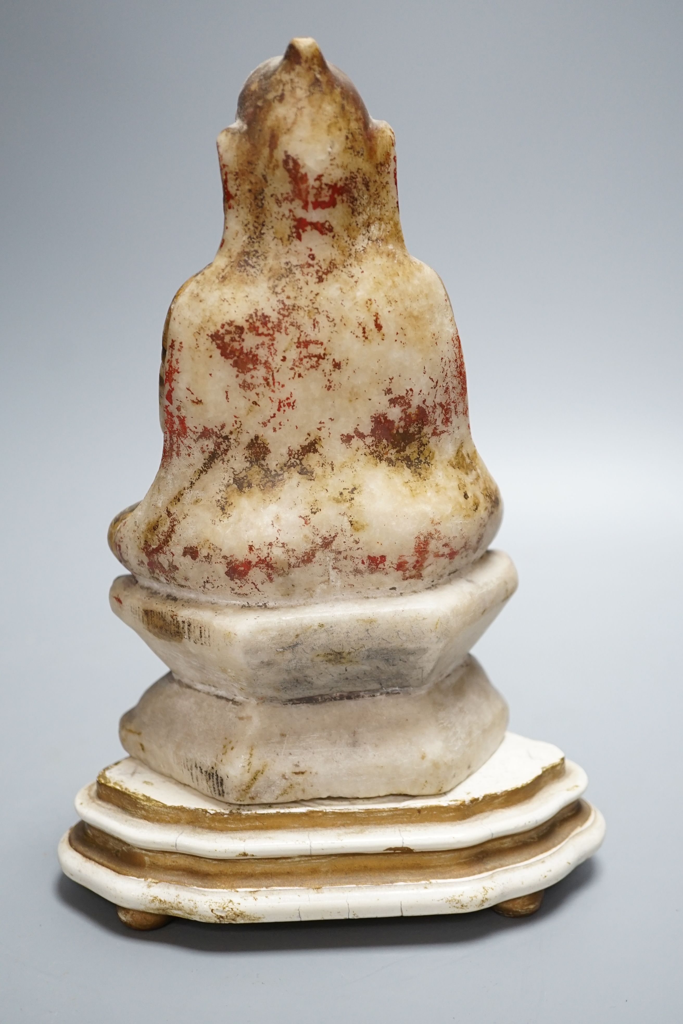 A late 19th century Indian carved alabaster seated figure, on associated wooden stand, 26cm